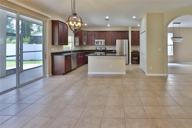 kitchen with dark countertops, a sink, arched walkways, a chandelier, and appliances with stainless steel finishes