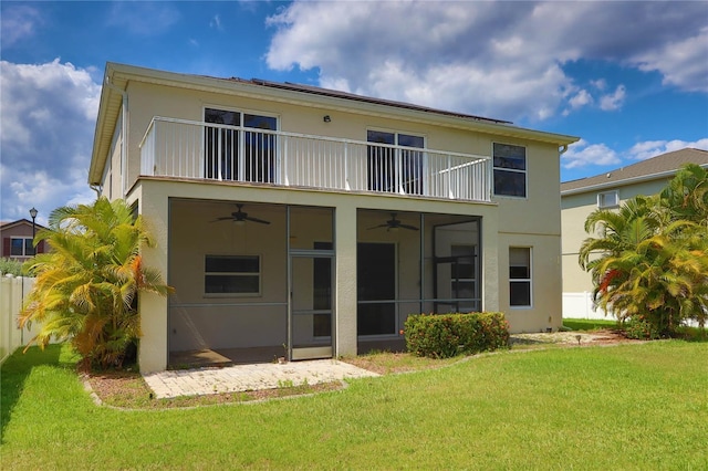 back of property featuring stucco siding, ceiling fan, a yard, and a balcony