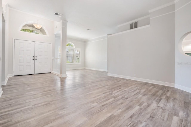 entrance foyer with wood finished floors, decorative columns, visible vents, and crown molding