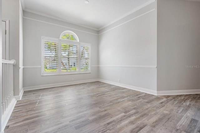 unfurnished room with wood finished floors, crown molding, and baseboards