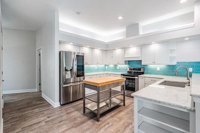 kitchen featuring open shelves, stainless steel appliances, a sink, and light wood finished floors