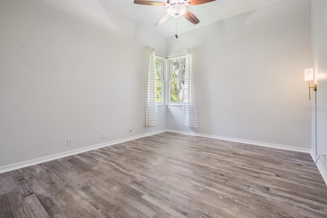 empty room with ceiling fan, baseboards, and wood finished floors