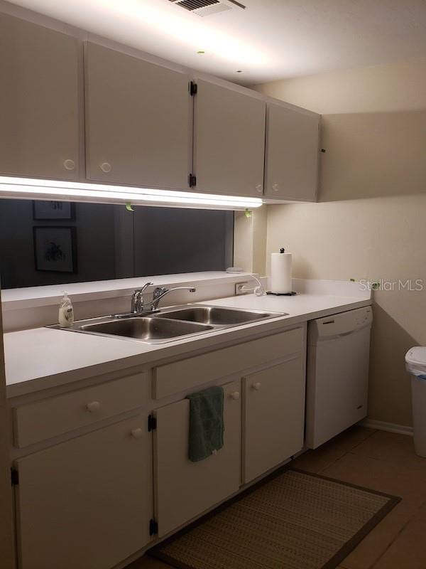kitchen with light tile patterned floors, light countertops, white dishwasher, white cabinets, and a sink