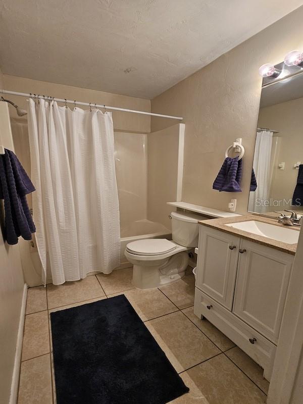 bathroom with toilet, vanity, shower / bath combination with curtain, and tile patterned floors