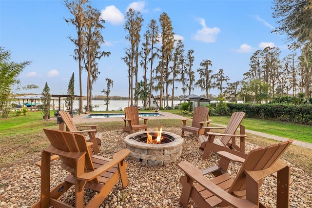 view of home's community featuring a yard, a swimming pool, a water view, and an outdoor fire pit