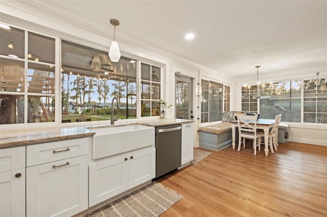 kitchen with stainless steel dishwasher, crown molding, a sink, an inviting chandelier, and light wood-style flooring