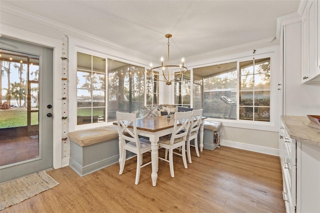 dining room featuring a chandelier, light wood-style flooring, baseboards, and ornamental molding