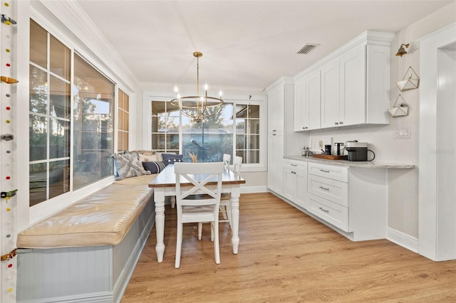 dining room featuring ornamental molding, a notable chandelier, visible vents, and light wood-type flooring