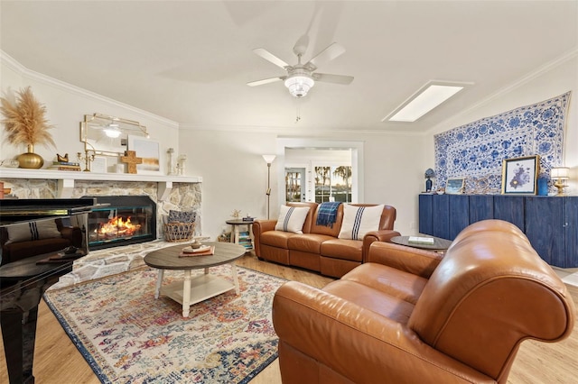 living room featuring a ceiling fan, wood finished floors, a fireplace, and crown molding