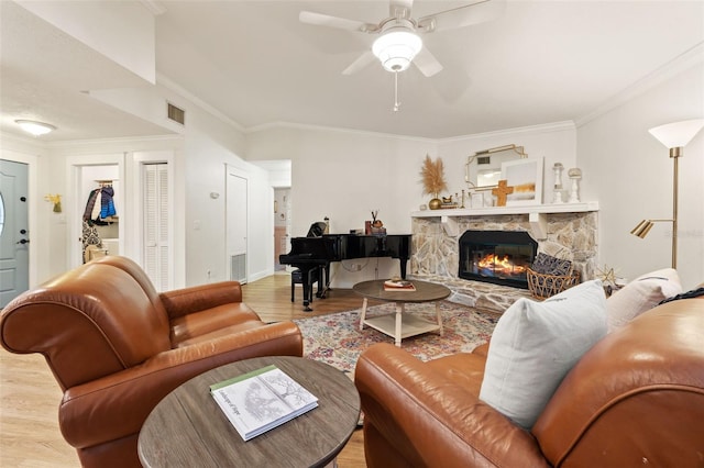 living room featuring a fireplace, wood finished floors, visible vents, and a ceiling fan