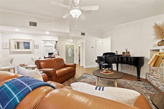 living area with wood finished floors, visible vents, and crown molding