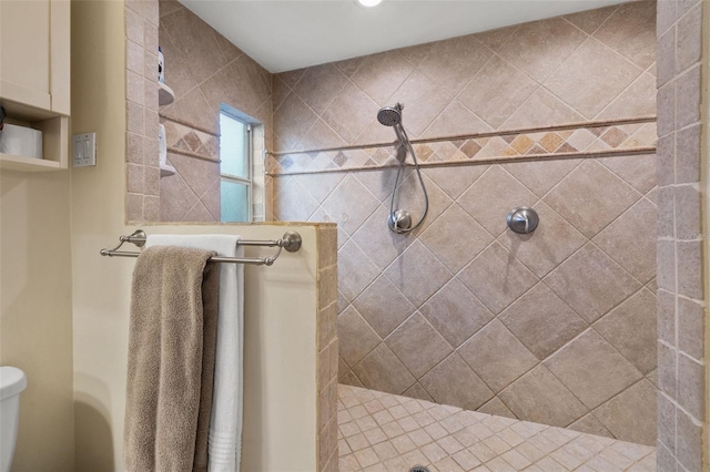 bathroom with a tile shower and toilet
