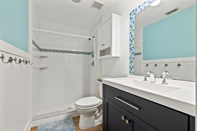 full bathroom with wood finished floors, visible vents, a tile shower, and toilet