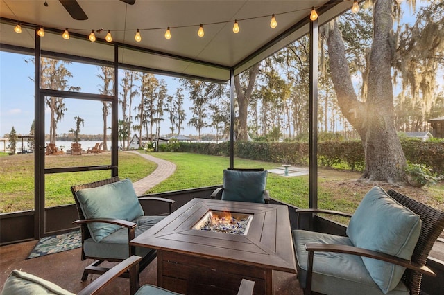 sunroom with ceiling fan, a water view, an outdoor fire pit, and a healthy amount of sunlight