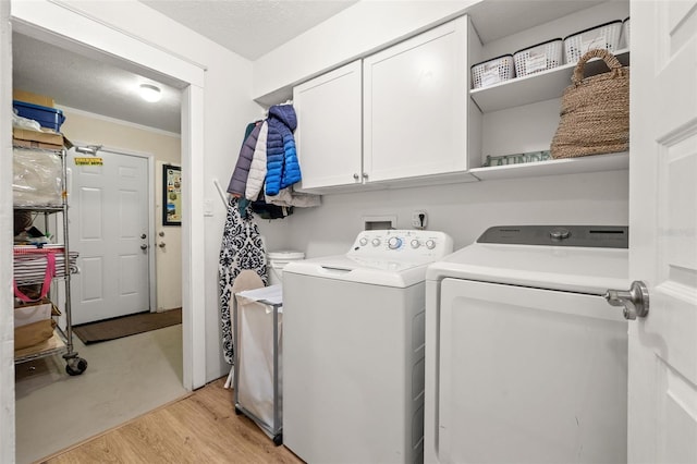 laundry area with cabinet space, independent washer and dryer, and light wood-type flooring