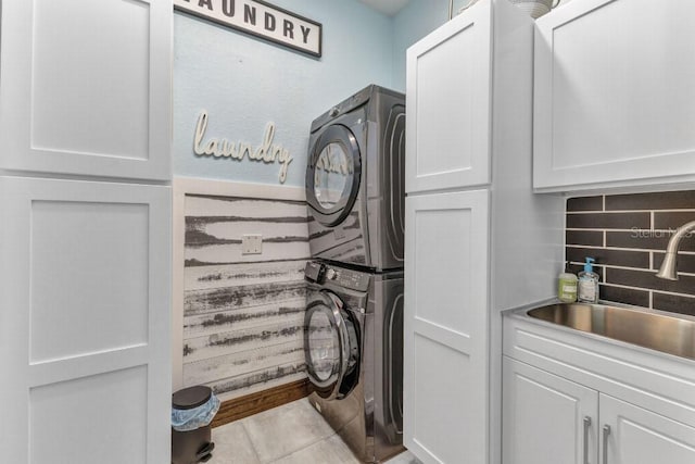 107 Sunset Dr, Nokomis, FL 34275 - clothes washing area with cabinet space, stacked washing maching and dryer, tile patterned floors, and a sink