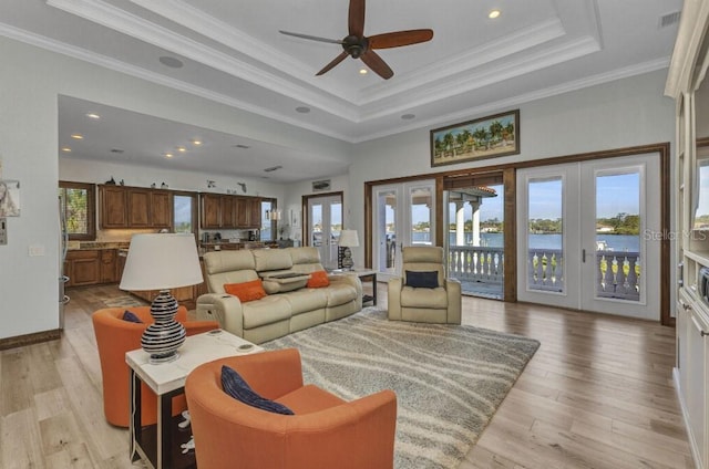 107 Sunset Dr, Nokomis, FL 34275 - living room with crown molding, light wood-type flooring, ceiling fan, french doors, and a tray ceiling