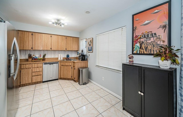 kitchen featuring a sink, light tile patterned floors, baseboards, light countertops, and appliances with stainless steel finishes