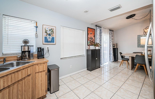 kitchen featuring light tile patterned floors, a sink, visible vents, light countertops, and baseboards
