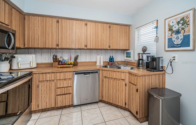 kitchen featuring light tile patterned floors, a sink, stainless steel appliances, and light countertops