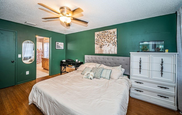 bedroom featuring wood-type flooring, a textured ceiling, visible vents, and a ceiling fan