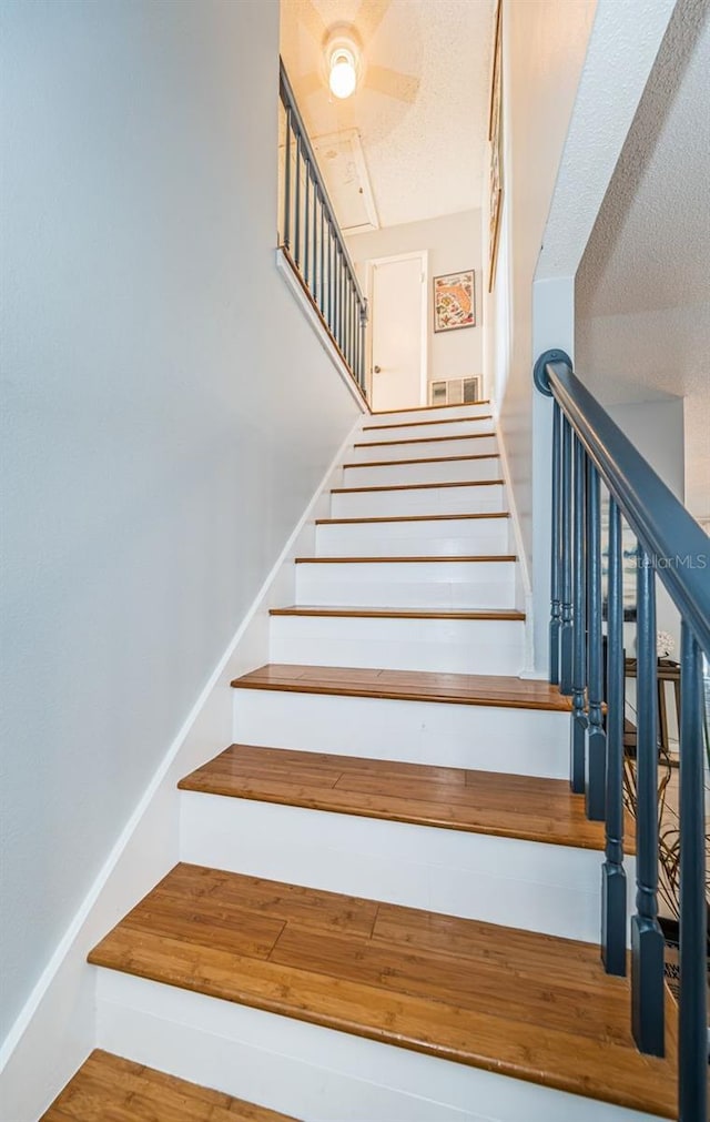 stairway featuring wood finished floors and visible vents