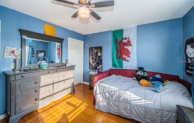 bedroom with a textured ceiling, ceiling fan, wood finished floors, and baseboards