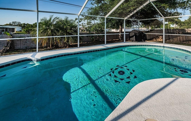 view of swimming pool featuring glass enclosure, a fenced in pool, and a fenced backyard