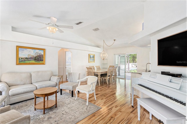 living area with light wood-style floors, lofted ceiling, visible vents, and ceiling fan