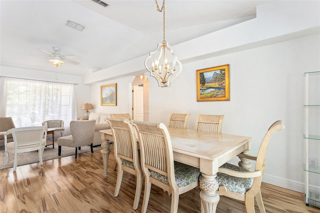 dining room with ceiling fan with notable chandelier, light wood-style flooring, baseboards, lofted ceiling, and visible vents