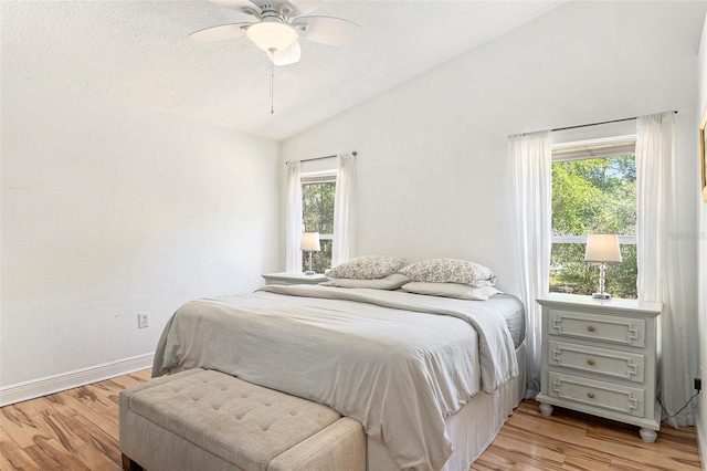 bedroom featuring a textured ceiling, ceiling fan, light wood finished floors, baseboards, and lofted ceiling