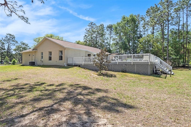 rear view of property featuring central air condition unit, a lawn, stucco siding, and a deck