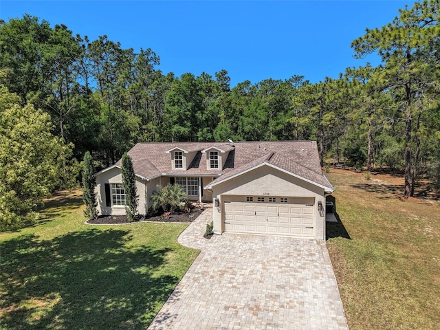 cape cod house with stucco siding, an attached garage, driveway, and a front lawn