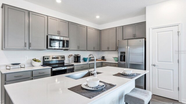 kitchen featuring light countertops, gray cabinets, stainless steel appliances, and a sink