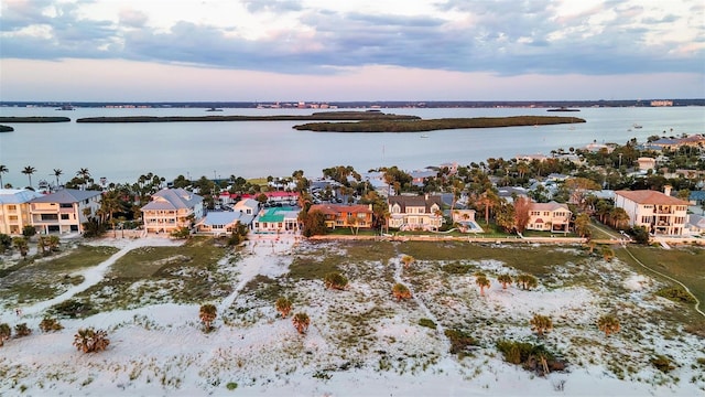 aerial view at dusk with a water view and a residential view