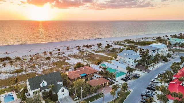 aerial view at dusk with a beach view and a water view
