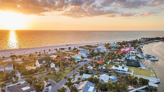 aerial view at dusk with a water view, a residential view, and a beach view