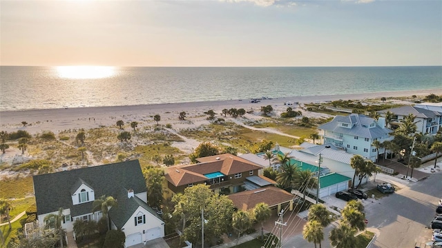 aerial view at dusk with a water view and a view of the beach