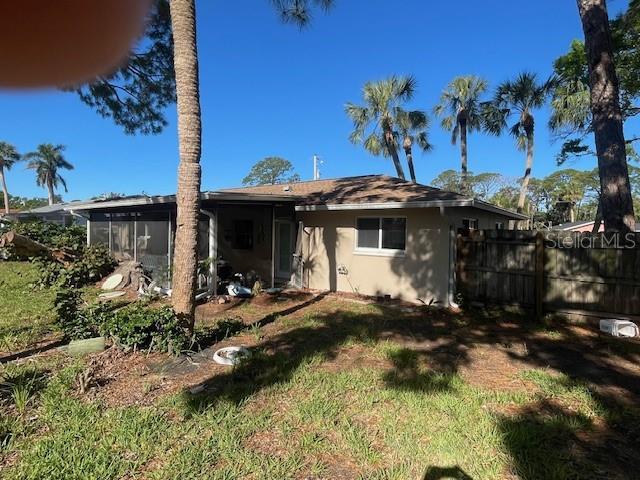 view of front of house with a front lawn, fence, stucco siding, and a sunroom