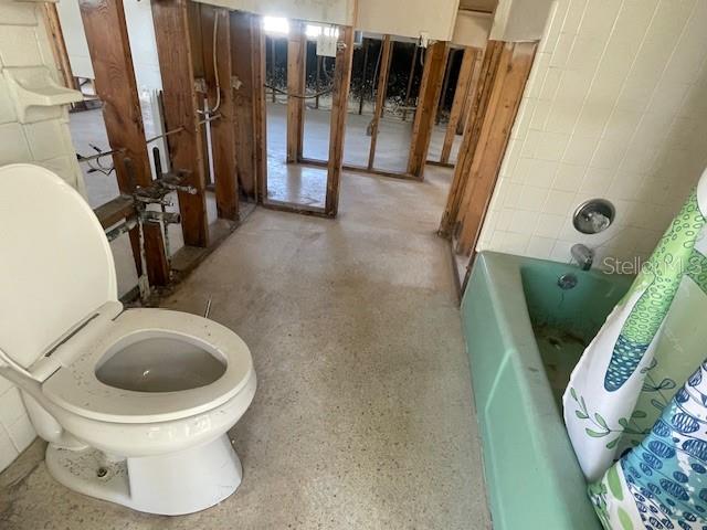 bathroom featuring shower / bathtub combination with curtain and toilet