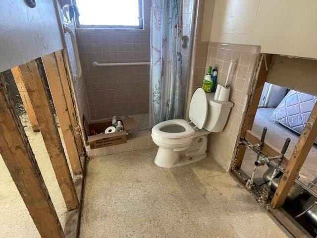 full bath with tile walls, a shower stall, and toilet