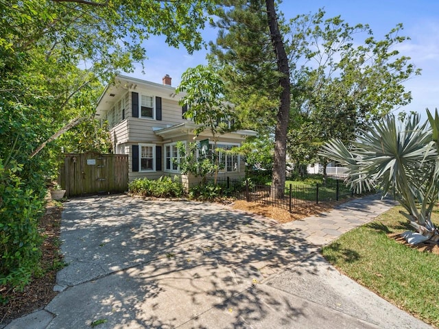 view of front of house featuring a chimney, a fenced front yard, a gate, and driveway