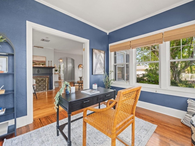 office with crown molding, arched walkways, visible vents, and wood finished floors