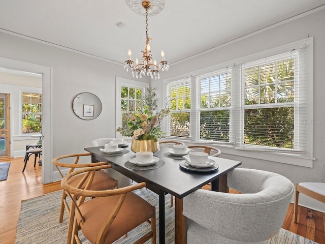 dining space with an inviting chandelier, light wood-type flooring, and ornamental molding