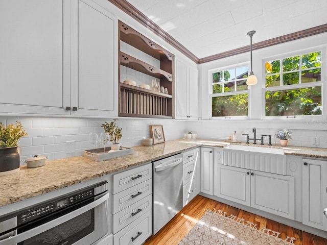 kitchen featuring backsplash, appliances with stainless steel finishes, light wood finished floors, and a sink