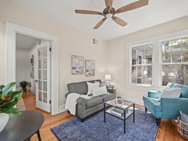 living room featuring baseboards, visible vents, wood finished floors, and ceiling fan