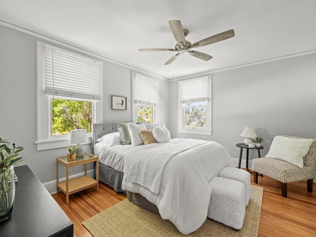 bedroom featuring ornamental molding, ceiling fan, and light wood-style flooring