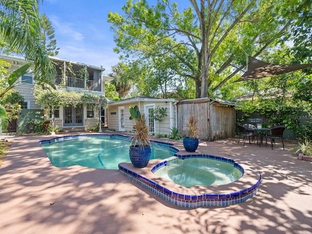 view of pool featuring a pool with connected hot tub, a patio, and french doors