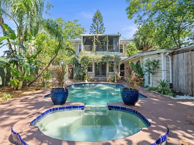 view of swimming pool featuring a pool with connected hot tub, a patio, and french doors
