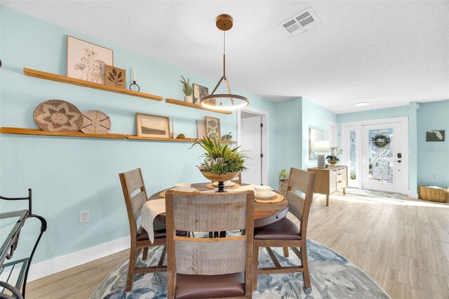 1015 Spindle Palm Way, Apollo Beach, FL 33572 - dining area with visible vents, baseboards, a textured ceiling, and wood finished floors